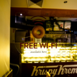 a donut shop with a free wifi sign in the window — Foto por 0xk na Unsplash