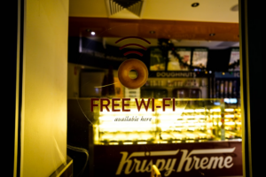 a donut shop with a free wifi sign in the window — Foto por 0xk na Unsplash