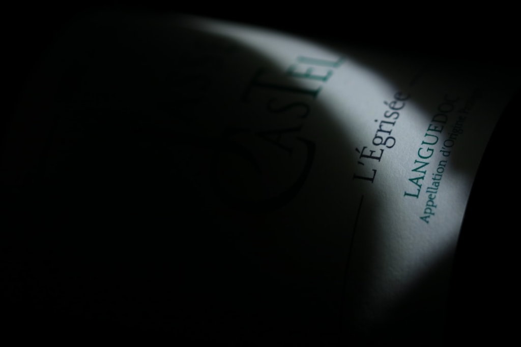 a close up of a bottle of wine in the dark — Foto por Rémi Rivière na Unsplash