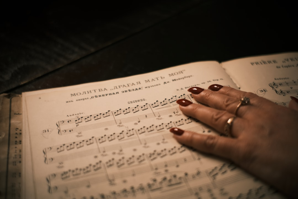 Woman's hand resting on sheet music — Foto por Maksim Zinchenko na Unsplash