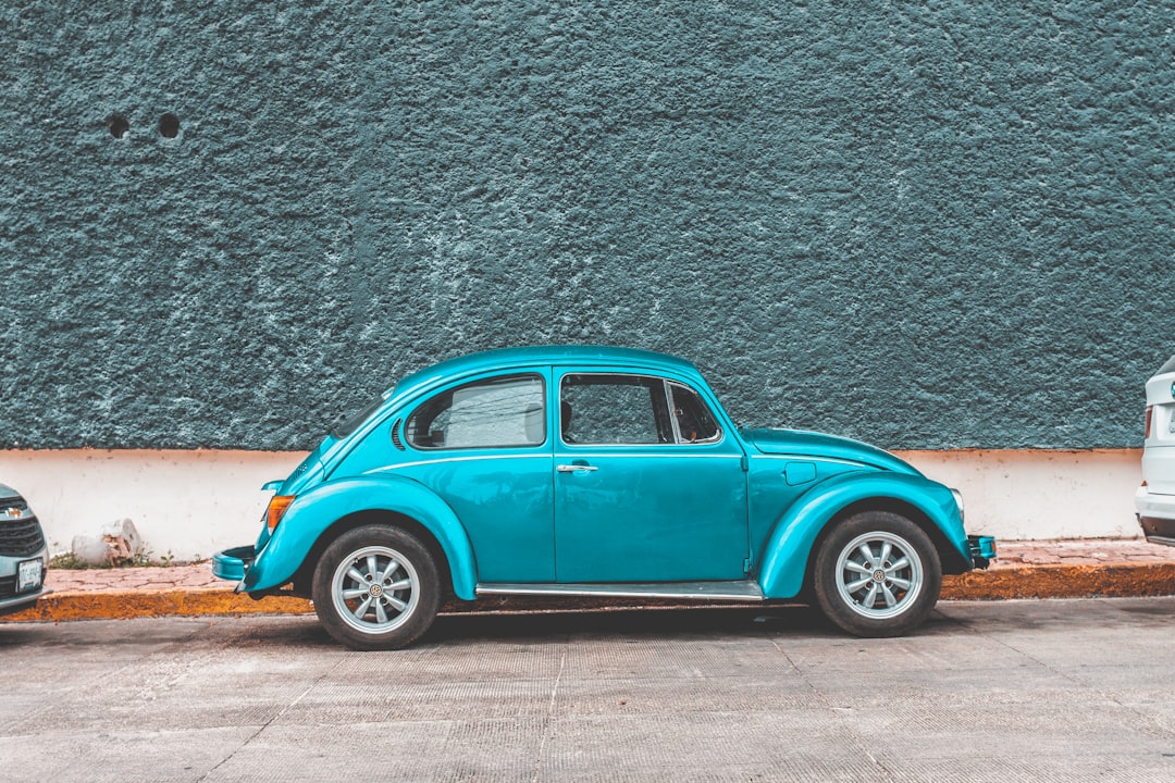 teal Volkswagen Beetle car parked beside sidewalk — Foto por Erik Odiin na Unsplash